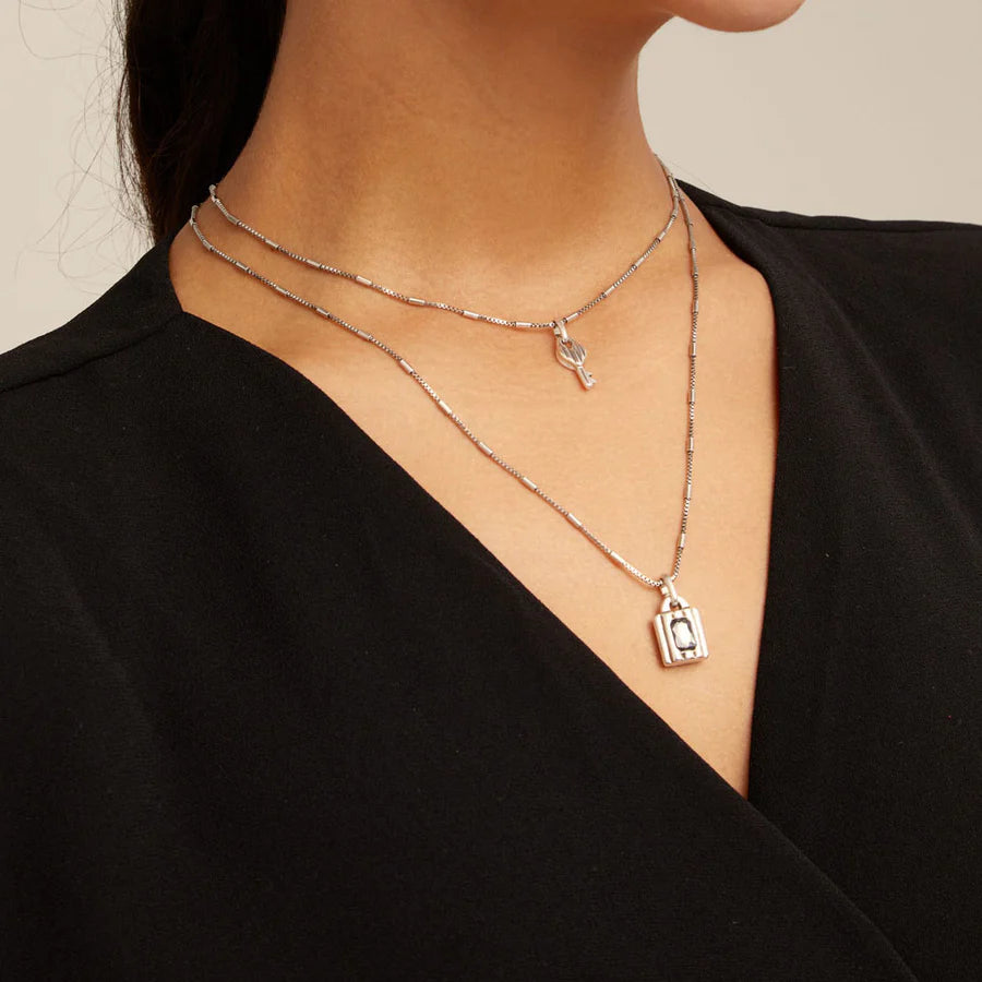 Close-up of a person wearingUNOde50 Lock Silver Double Strand Necklace with Key and Lock with Crystal on a plain background