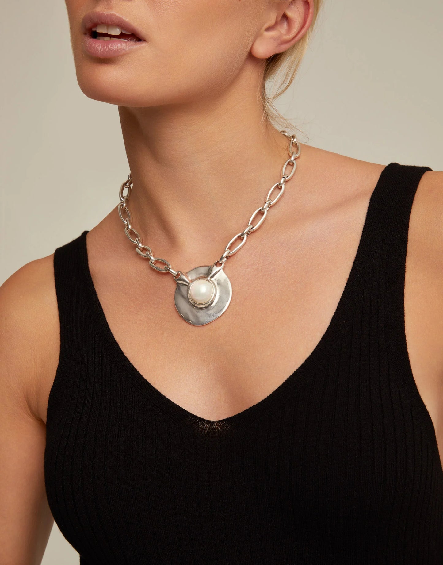 Woman wearing a black shirt with an UNOde50 Ovni Silver Chain Link Necklace with large Silver and Pearl Pendant 