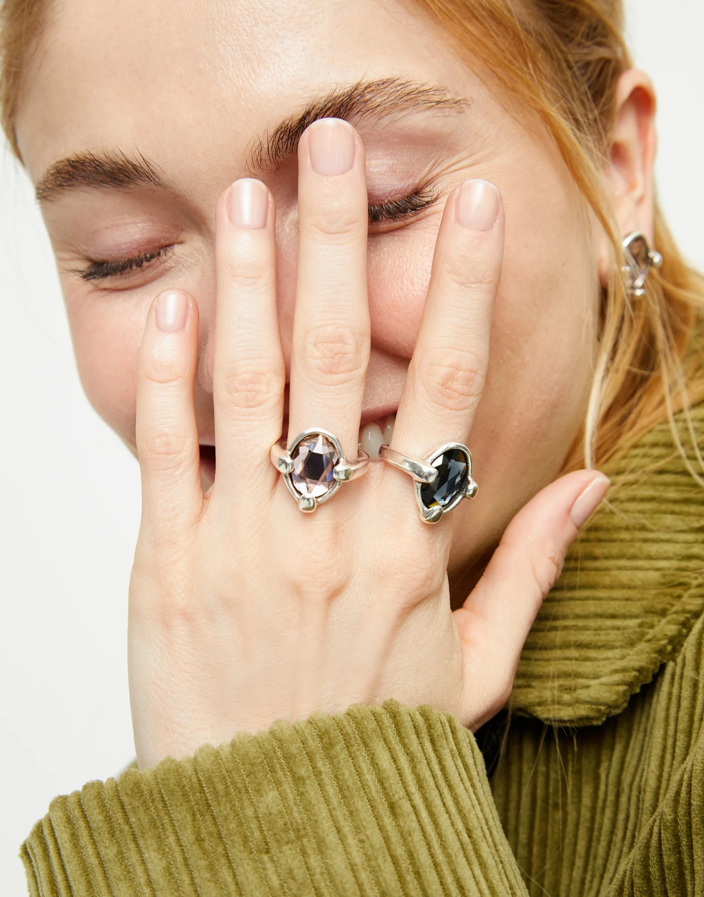Woman wearing two UNOde50 Ser Deslumbrante Silver Rings with Pink and black Oval Crystals on a plain background