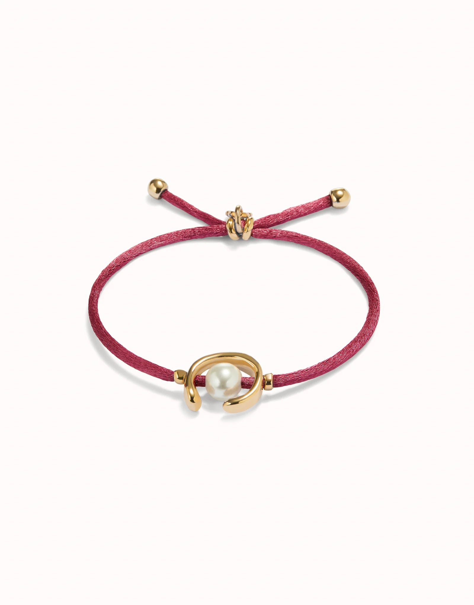 Bracelet with gold clasp and pearl charm on a red cord against a white background