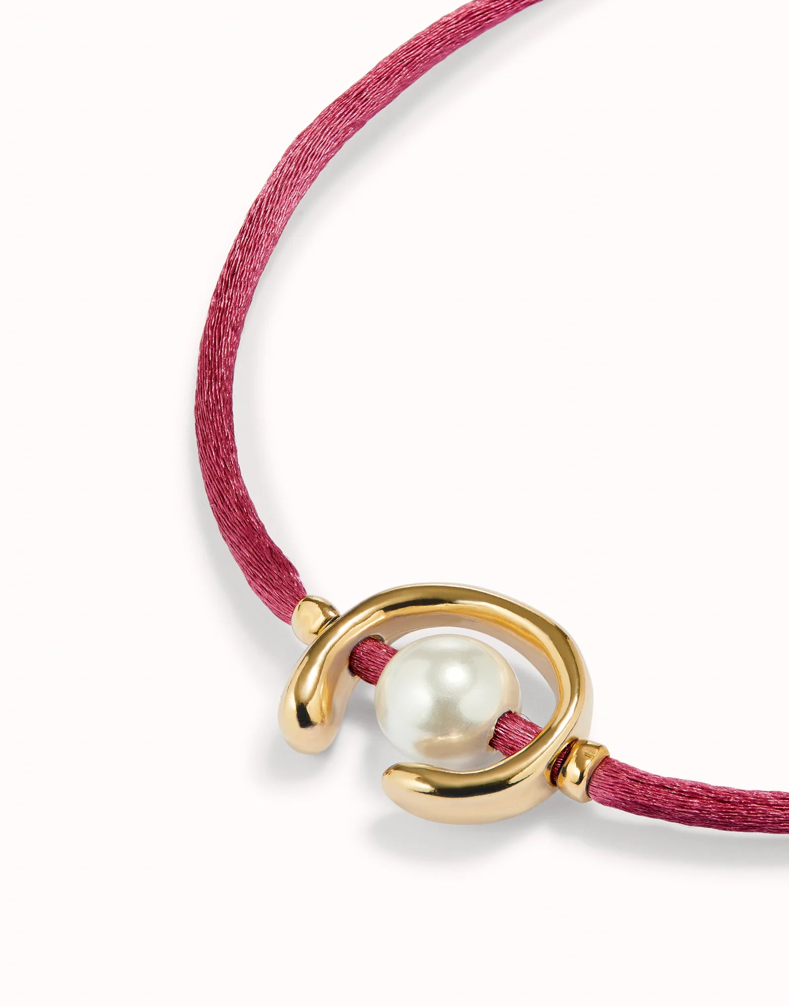 Bracelet with a pearl and gold clasp on a pink cord against a white background