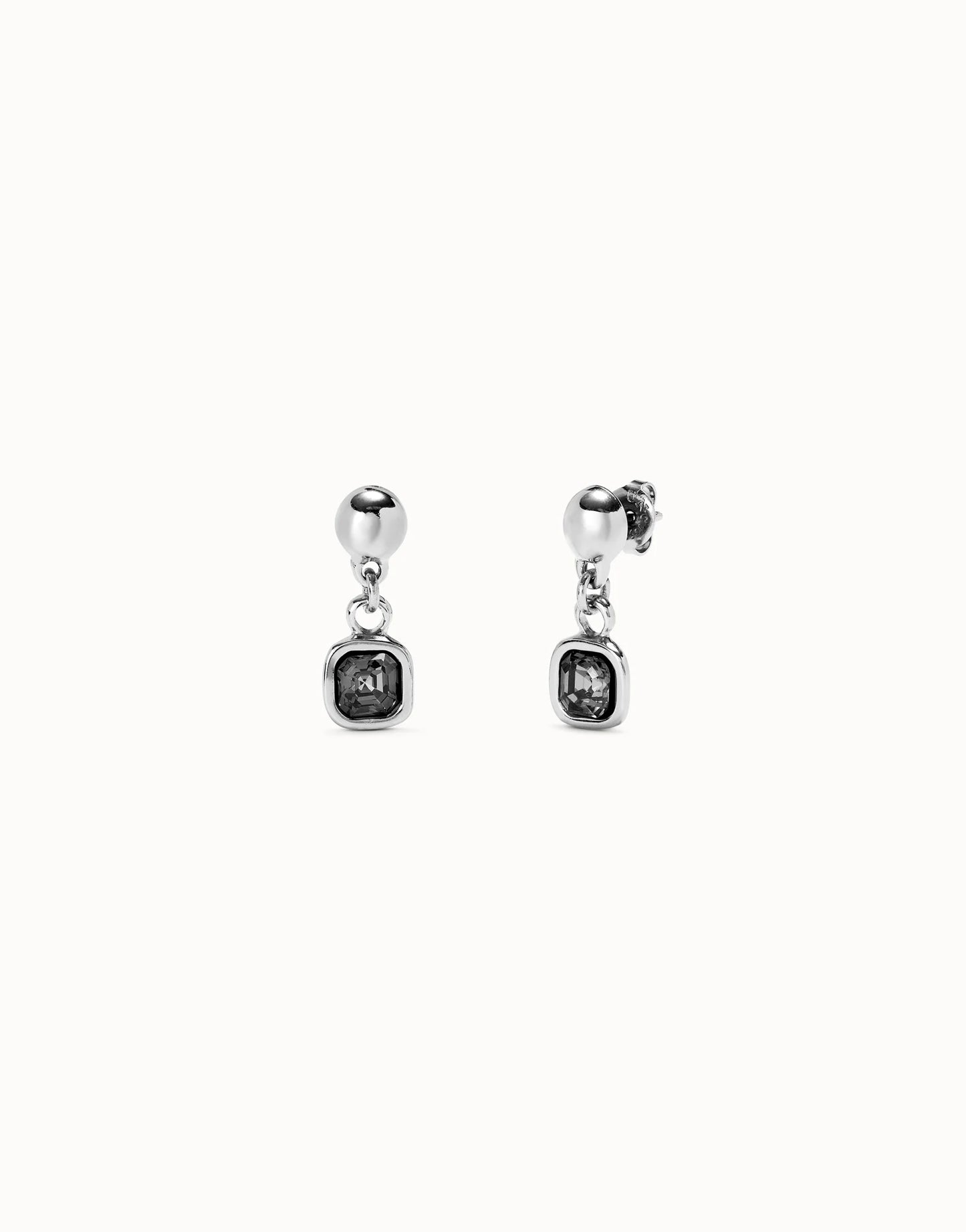 Pair of silver UNOde50 ser expresiva earrings with gemstones on a white background
