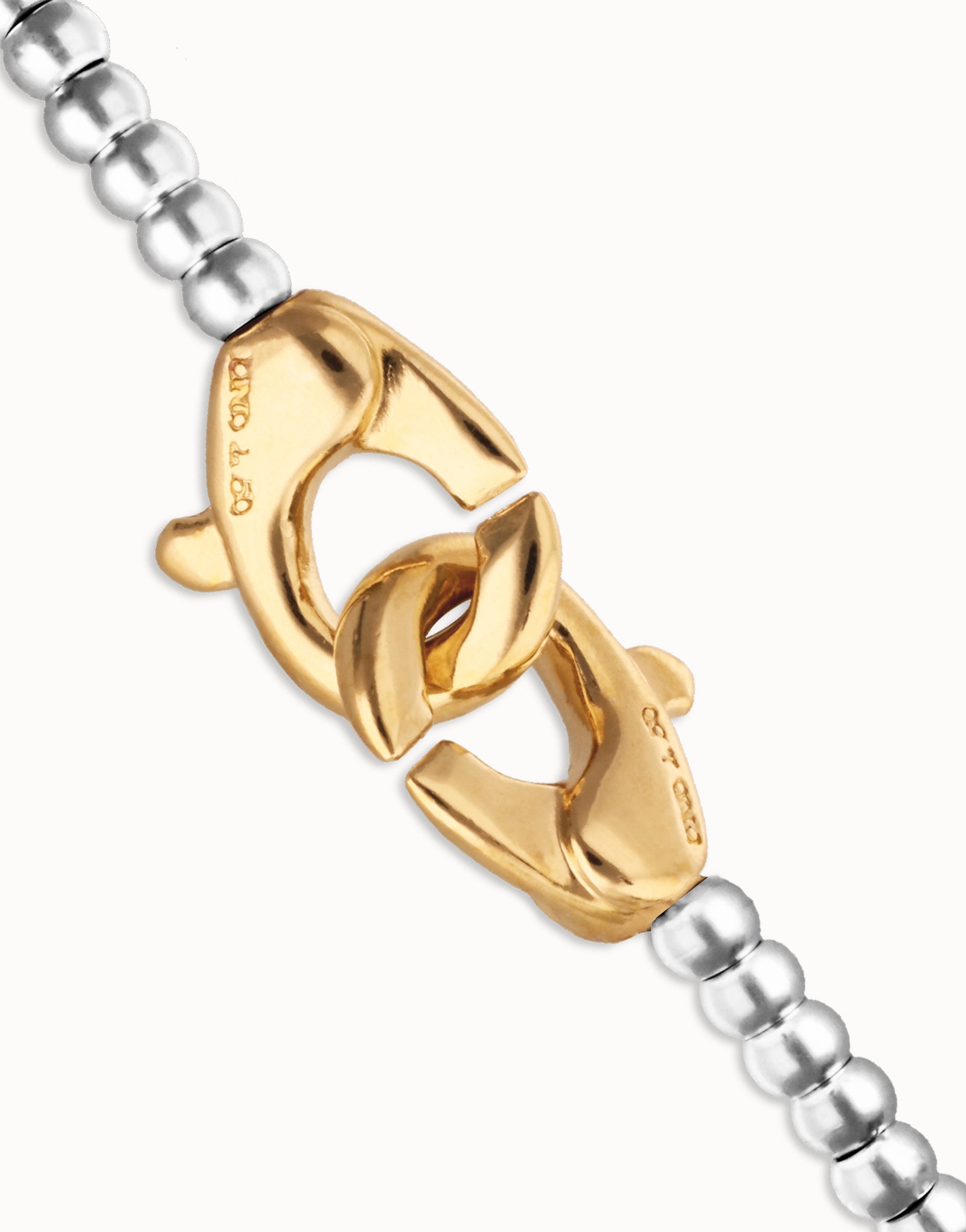 Close-up of a gold clasp on an UNOde50 silver bracelet on a white background