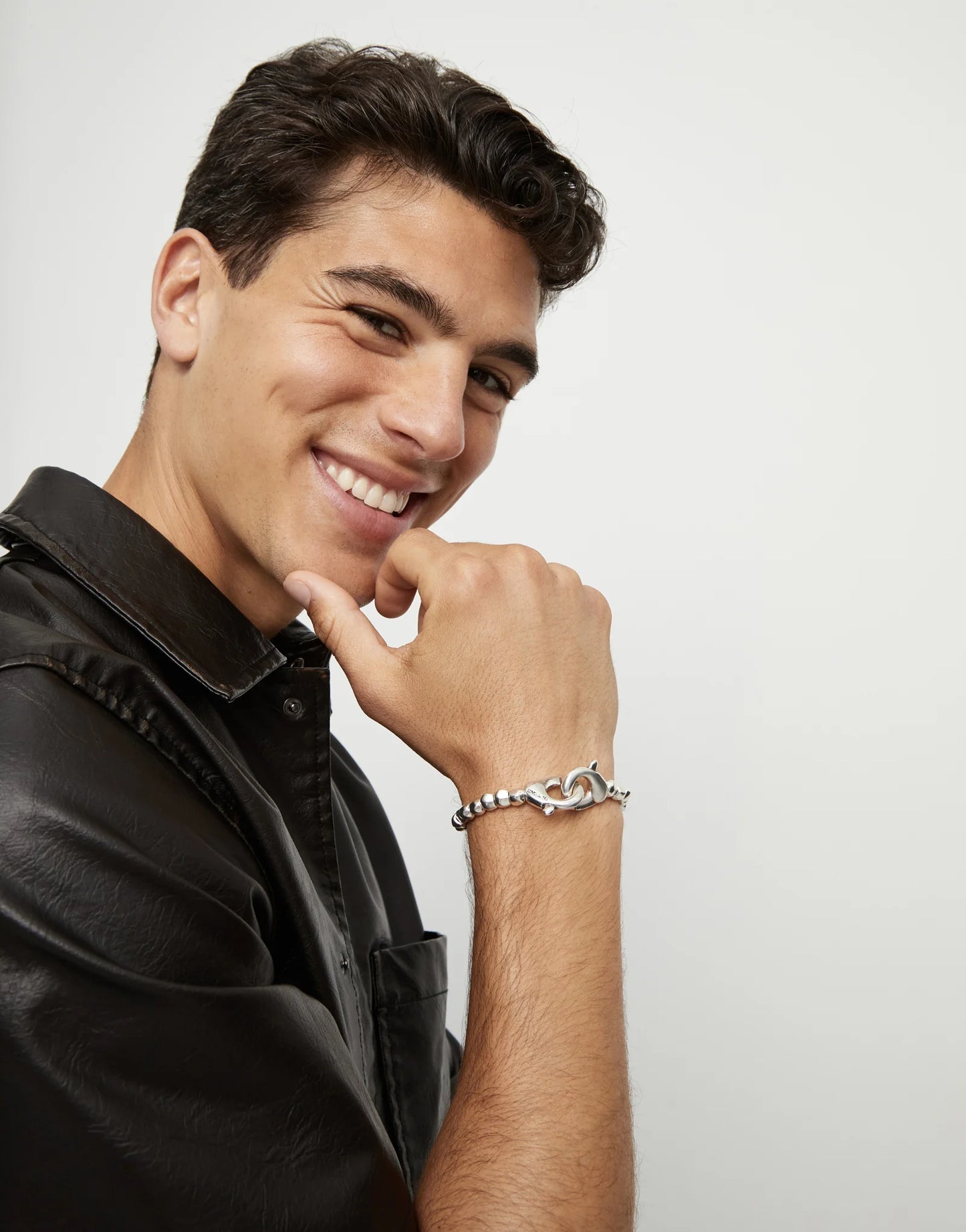 Man wearing a black leather jacket and UNOde50 Ser Inseparable Silver Sphere Beaded Bracelet on a light gray background