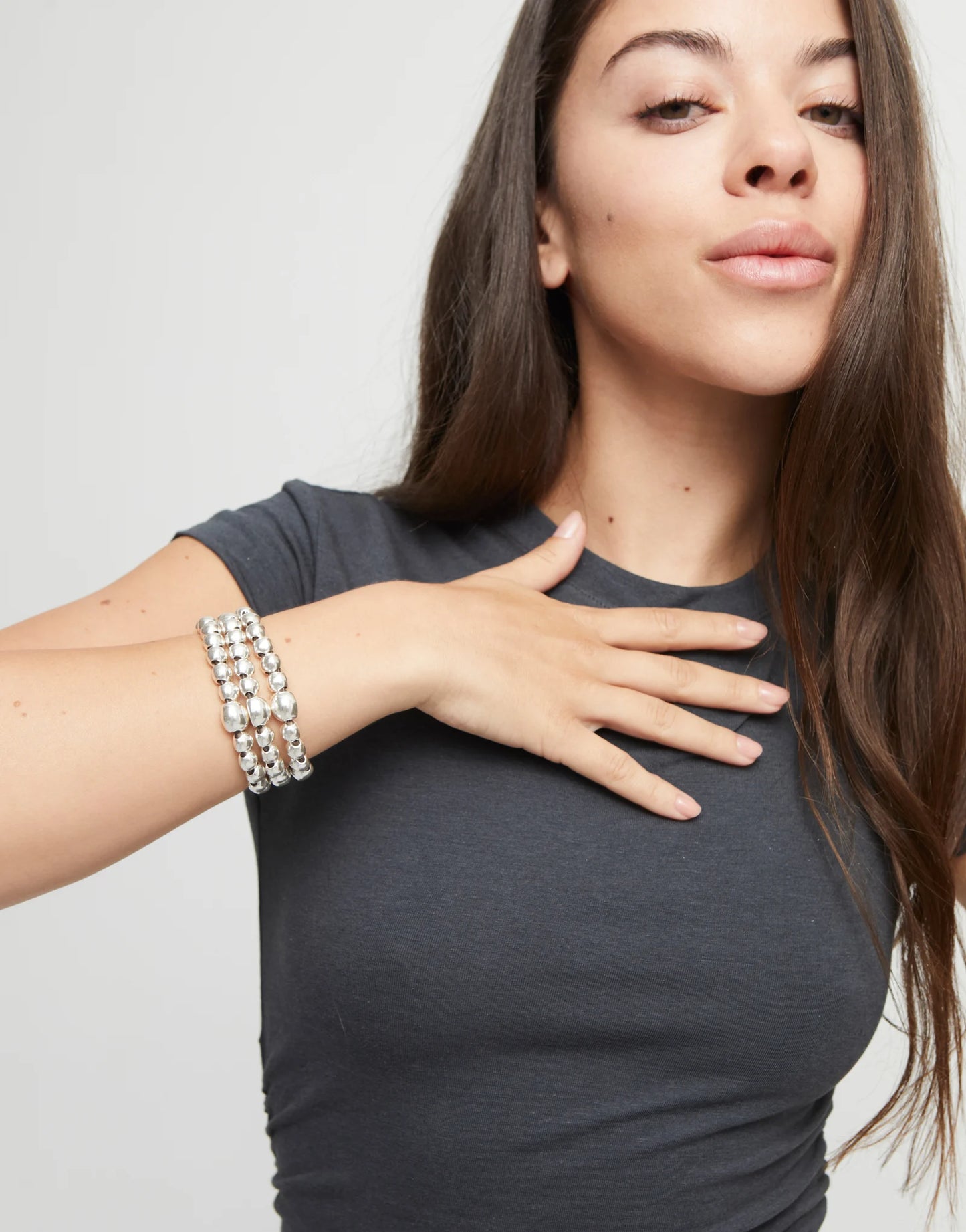 Girl in black shirt wearing an UNOde50 Ser Intrepida Three Strand Beaded Silver Bracelet with a white background