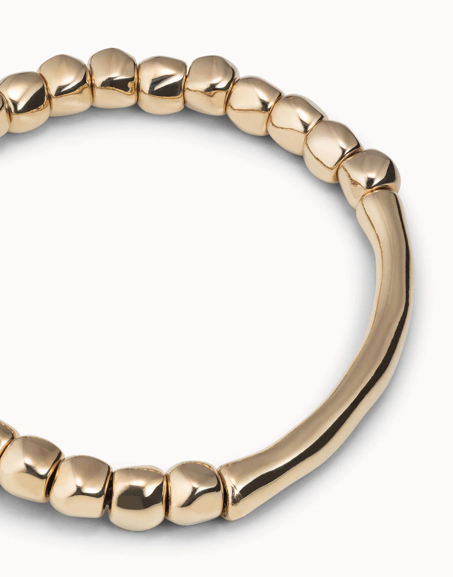 Close up of Gold beaded UNOde50 bracelet on a white background