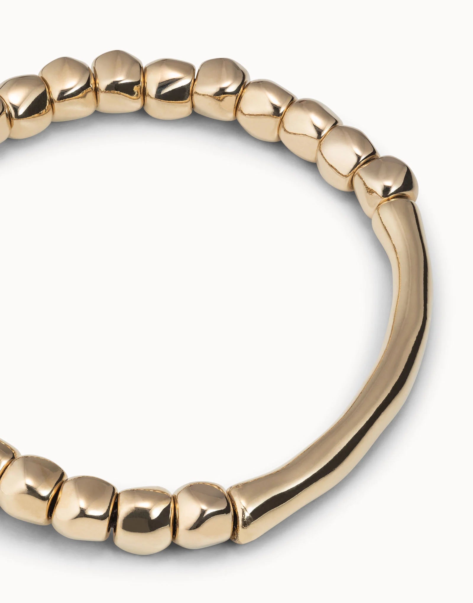 Close up of Gold beaded UNOde50 bracelet on a white background