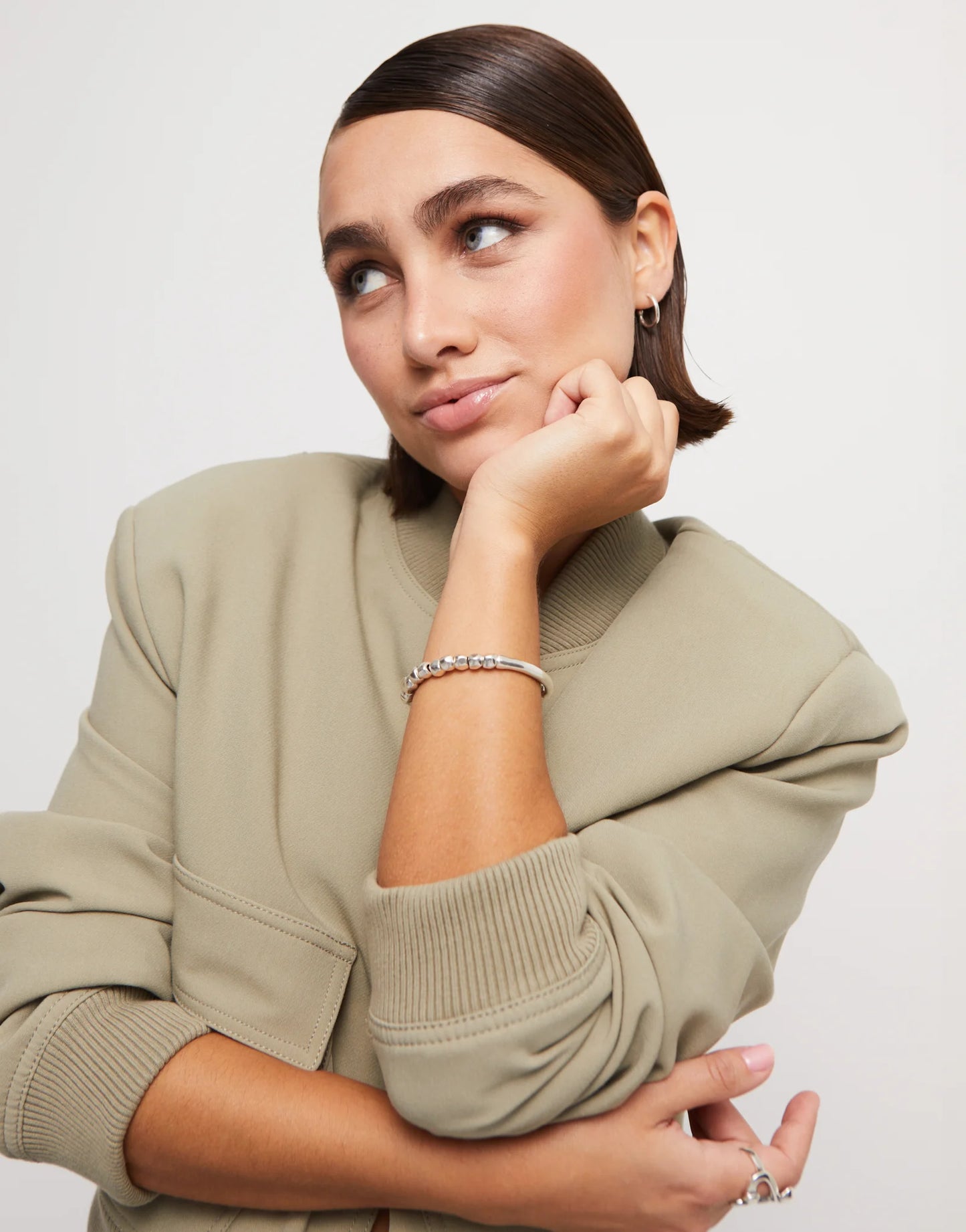 Woman wearing an UNOde50 Travesia Bracelet with Silver Beads and Tube-Shaped Accent  with a tan jacket and other UNOde50 jewelry
