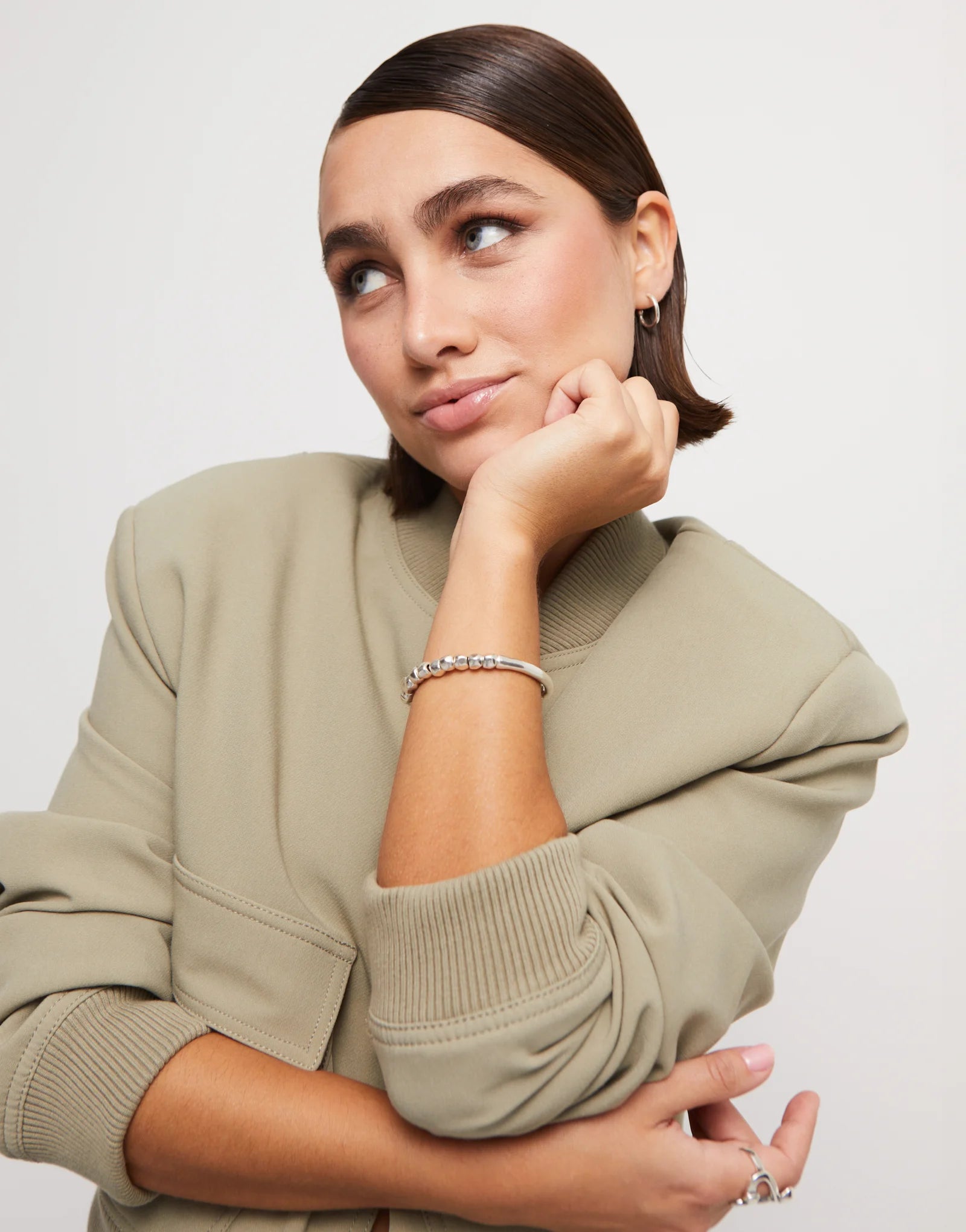 Woman wearing an UNOde50 Travesia Bracelet with Silver Beads and Tube-Shaped Accent  with a tan jacket and other UNOde50 jewelry
