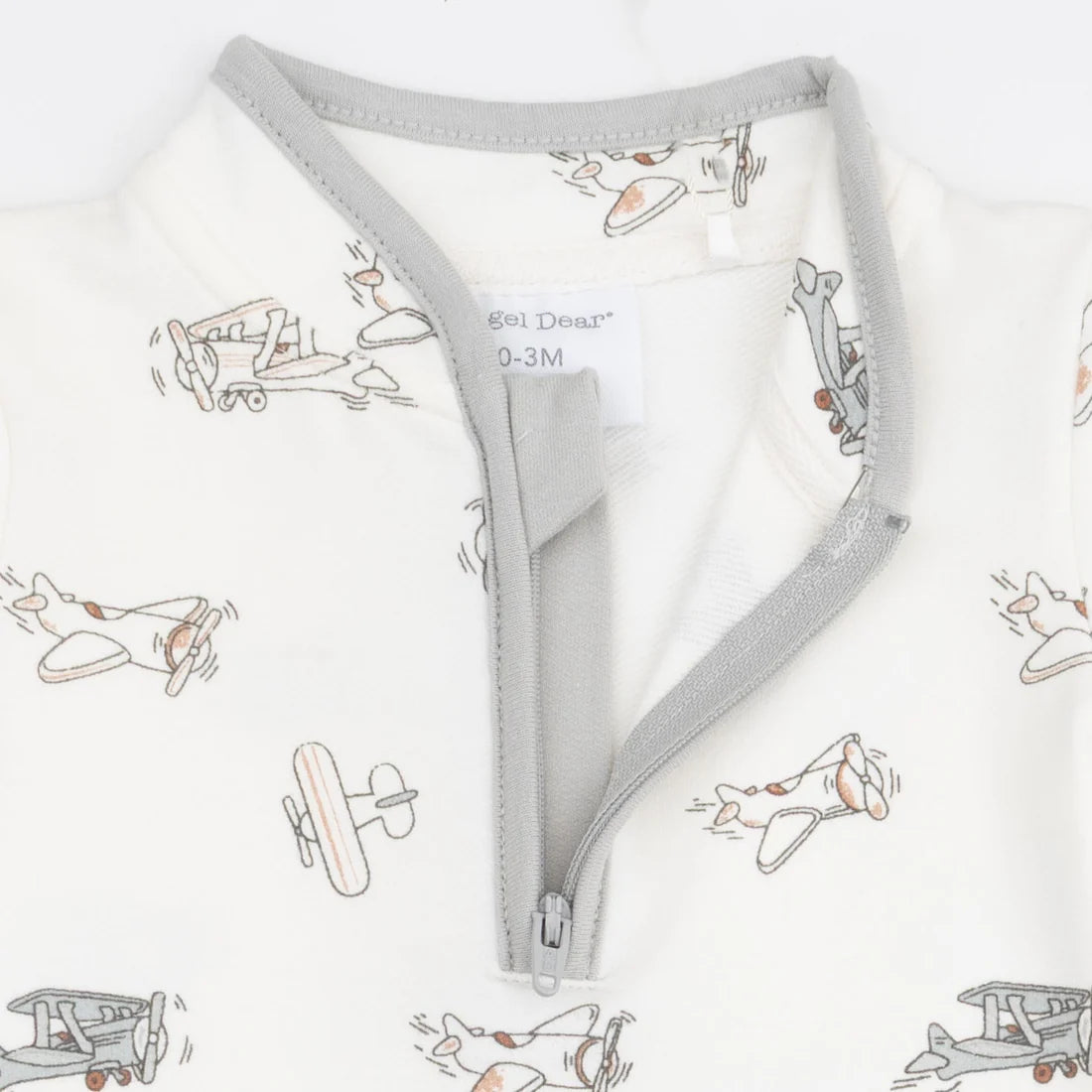 Close-up of a angel dear vintage pilots romper  with a light gray zipper and trim, featuring an off-white fabric printed with small vintage airplane illustrations. The brand name 'Goi Deer' is visible on the inner neck label.