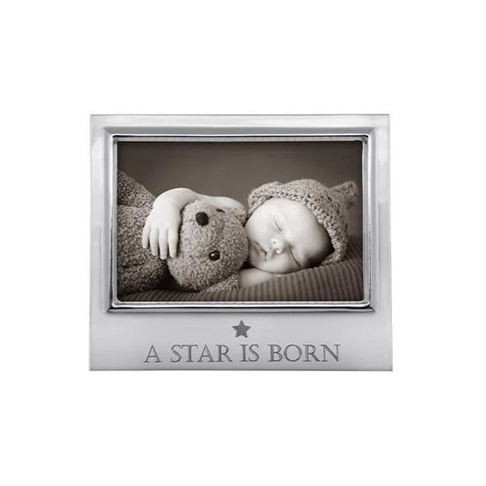 Silver photo frame with 'A Star is Born' engraving, containing a black and white photo of a baby and teddy bear.