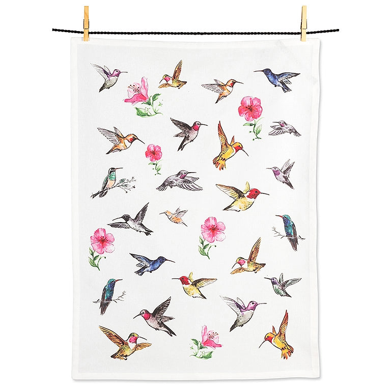 A white tea towel with a colorful pattern of hummingbirds and pink flowers, hanging from a black string with two wooden clothespins against a white background.