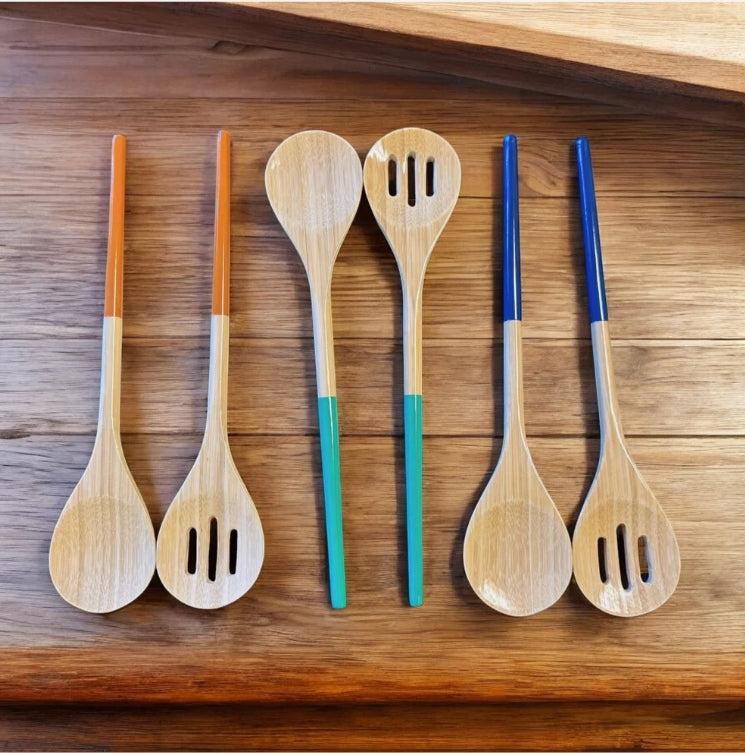 Set of wooden salad servers with colored handles on a wooden surface