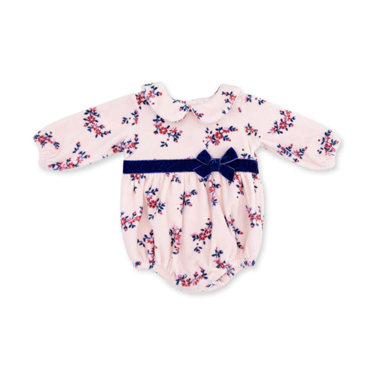 A baby long-sleeve romper in light pink velour with a navy and burgundy floral print, featuring a navy-blue velvet bow belt at the waist.