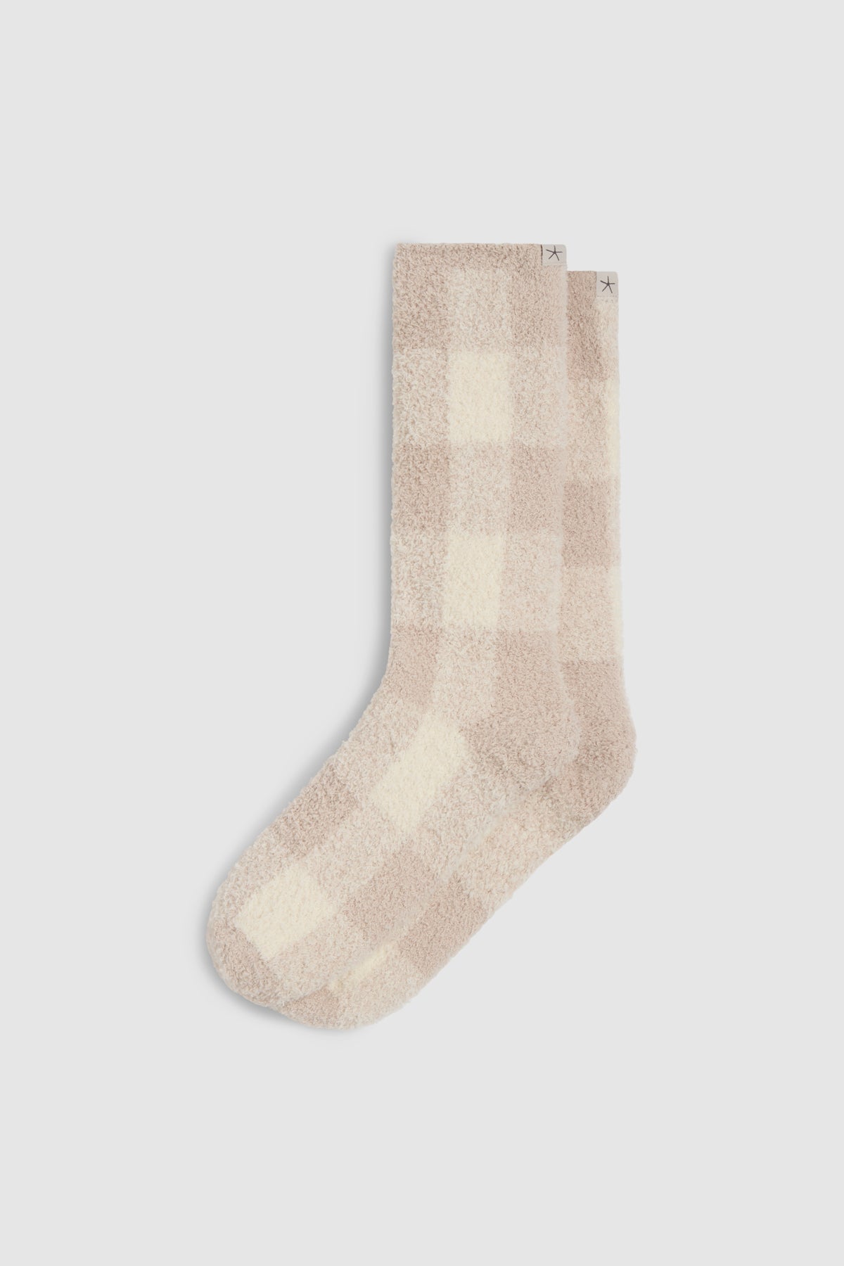 A pair of plush, fuzzy crew socks in a soft beige and cream buffalo check pattern, displayed against a light gray background.