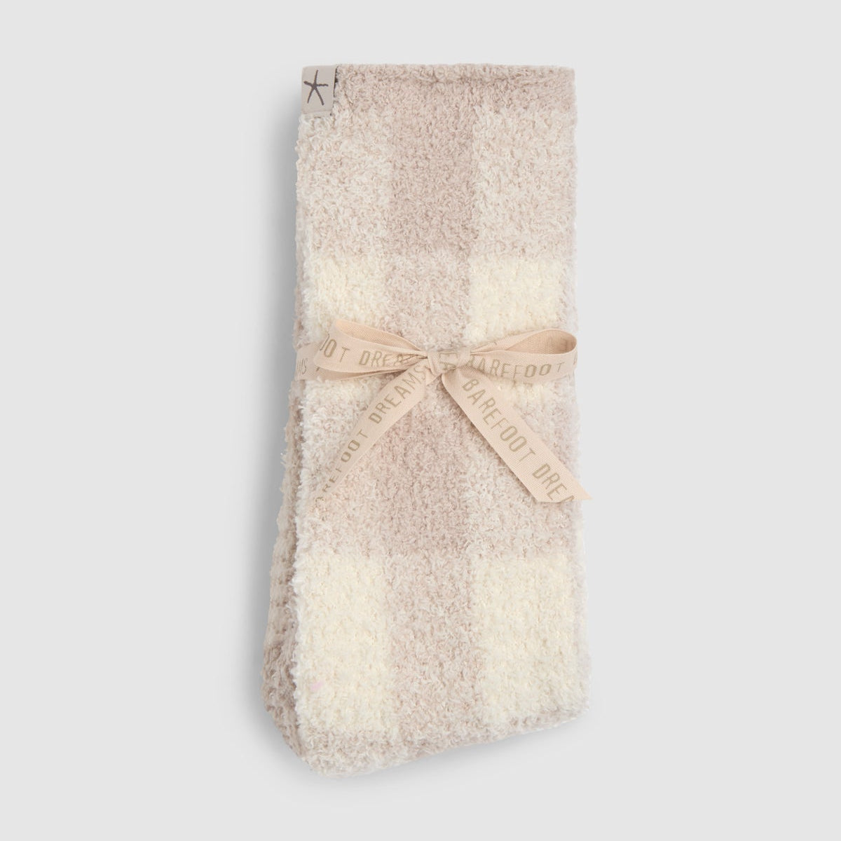 Folded plush fleece socks in a beige and cream checkered pattern, tied with a beige ribbon that reads 'BE GOOD TO EACH OTHER', on a light gray background.