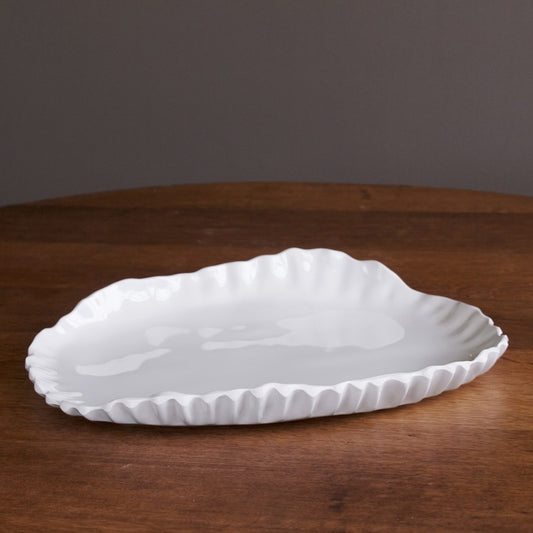 A white, oval-shaped, melamine serving platter with a fluted edge, designed for serving various foods.