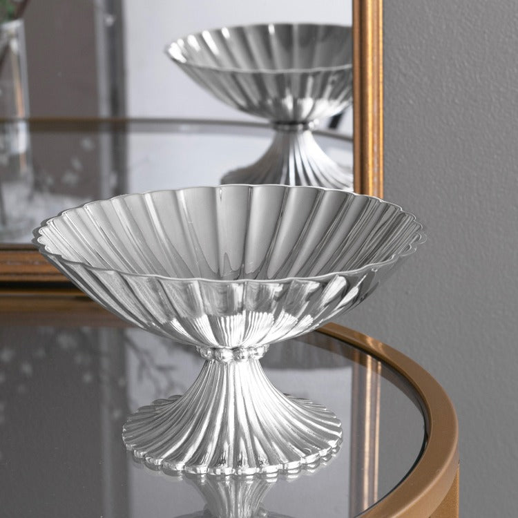 A silver-colored metal pedestal bowl with fluted surfaces 