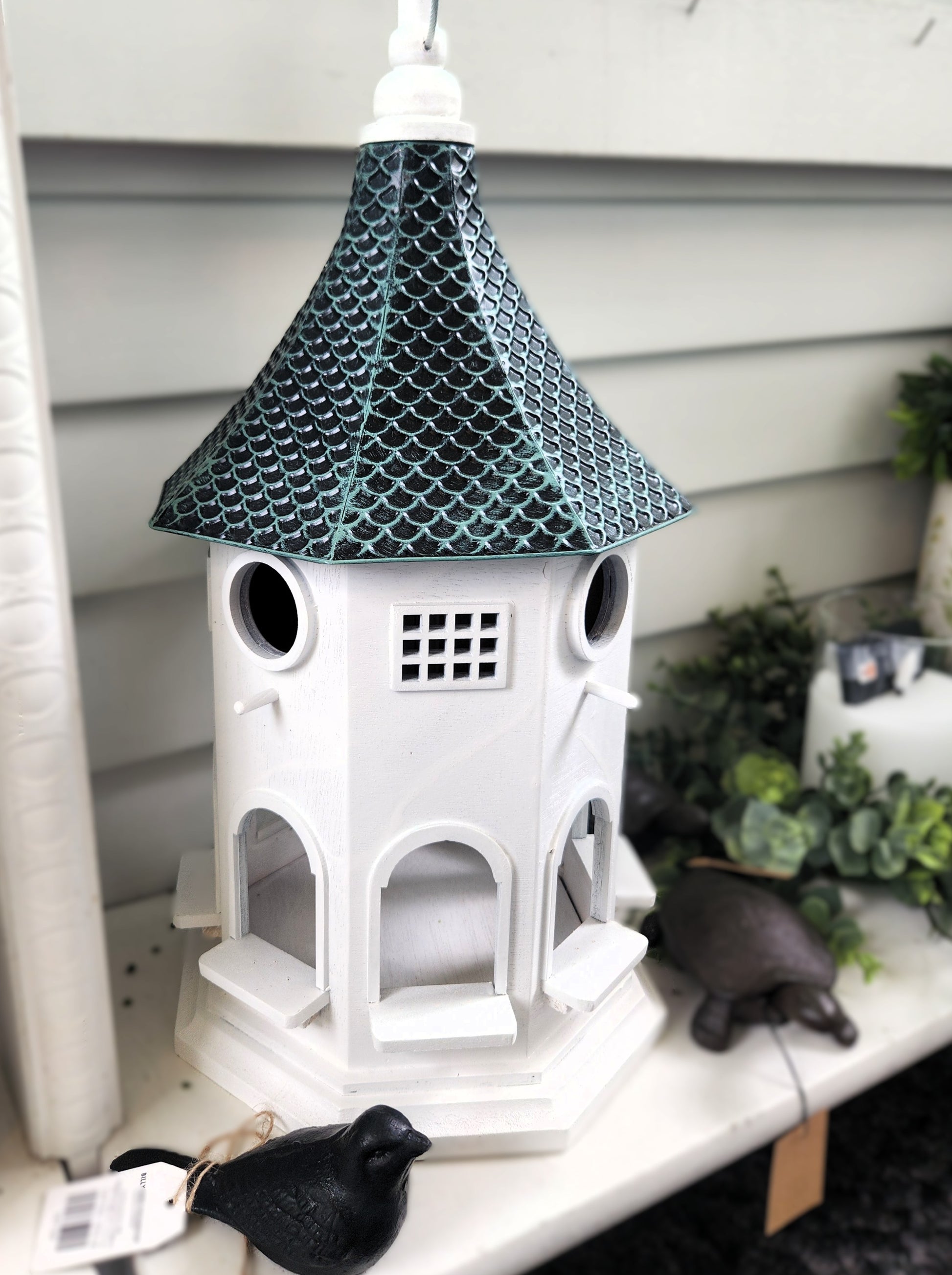 Decorative wood birdhouse with a tin roof on a shelf at The Little Exchange