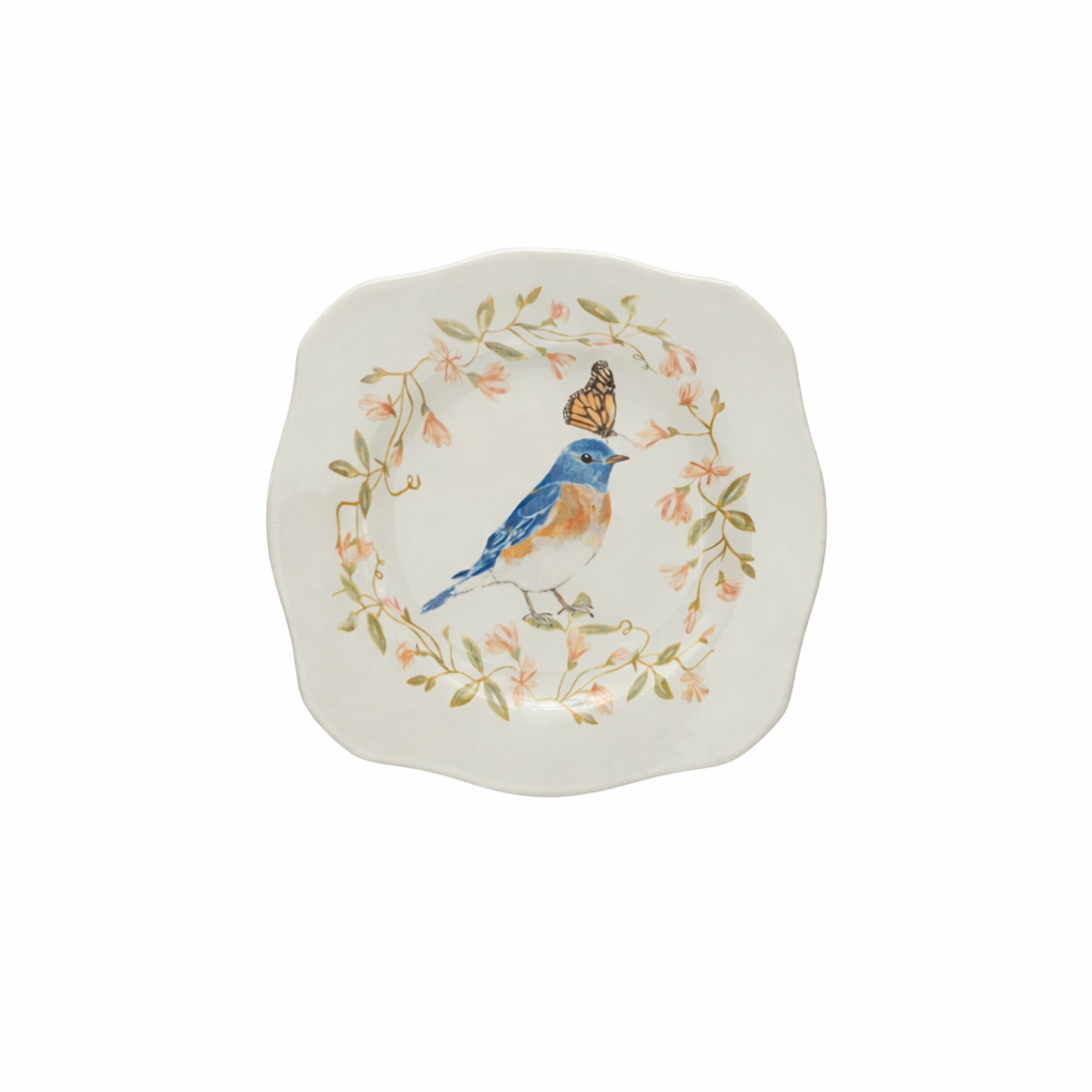 a stoneware plate featuring a bluebird in a ring of flowers