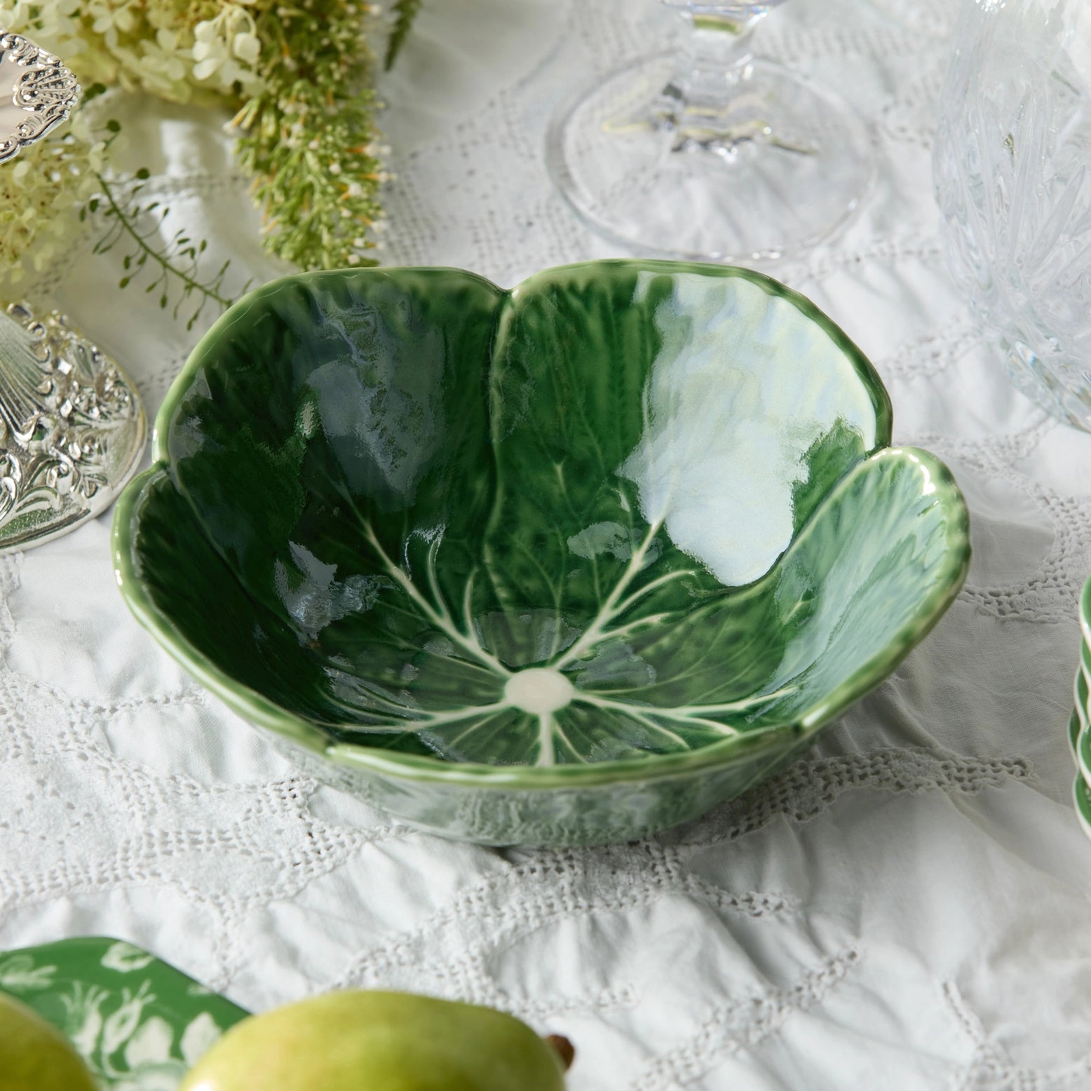 Green ceramic bowl with leaf design on a white lace tablecloth