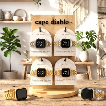 Display of apple smartwatch luxary bands on a wooden stand with 'cape diablo' branding, surrounded by plants and decor.