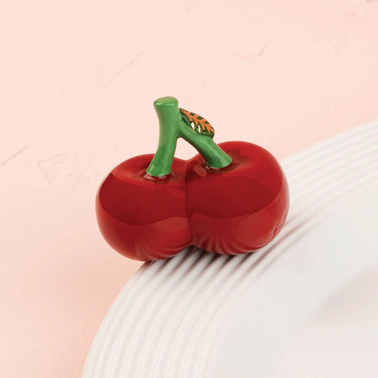 a nora fleming mini with a pair of red cherries with a green stem
