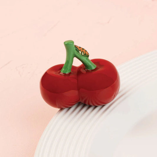a nora fleming mini with a pair of red cherries with a green stem