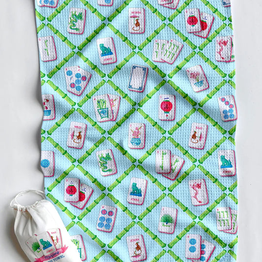 kitchen waffle towel with colorful mahjong tiles and a green bamboo lattice pattern on a turquoise background