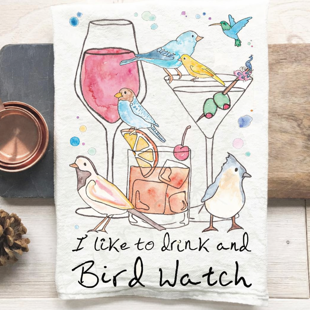 Tea towel with bird-themed design and text 'I like to drink and Bird Watch' on a wooden surface.