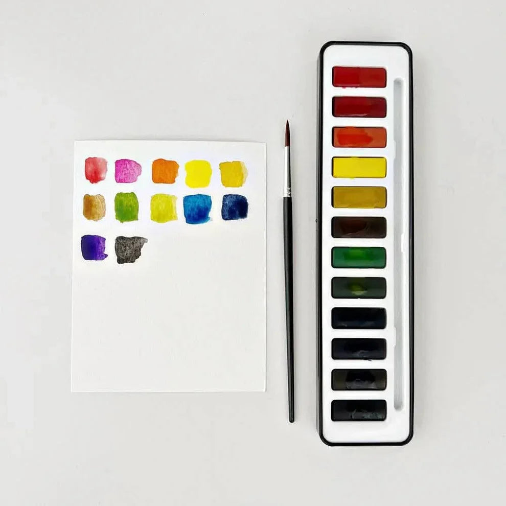 Set of watercolor paints with a color swatch on paper and a brush on a white background