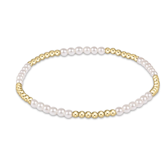enewton blissful bracelet with several 3mm Pearl beads alternating with several and 2.5mm gold beadst on a white background