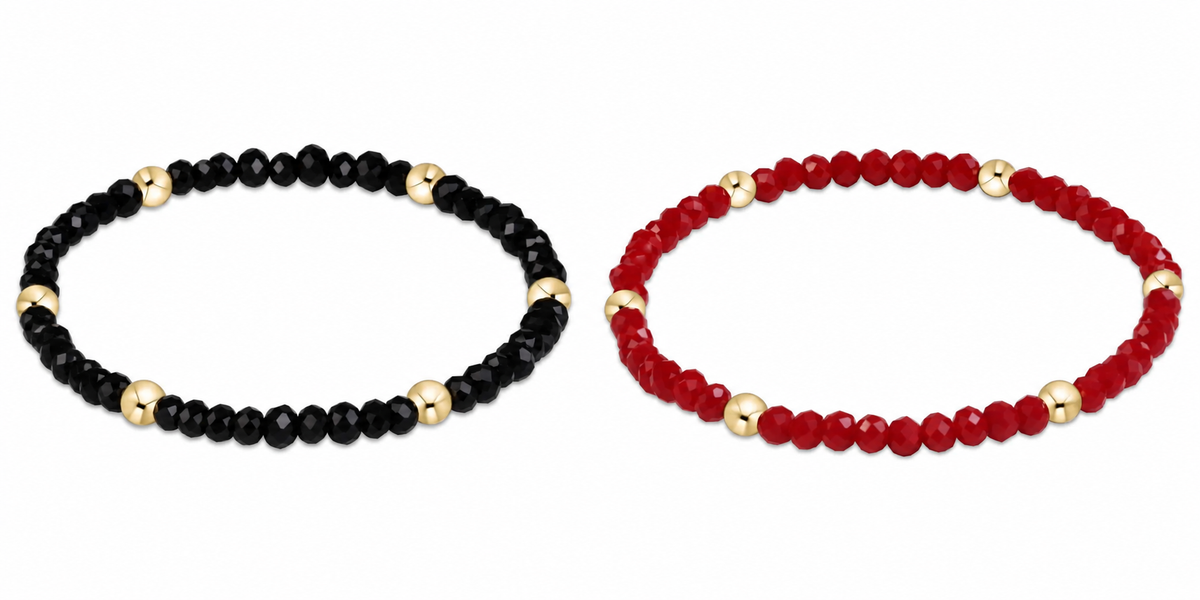 Two beaded enewton gameday flirty presence stretch bracelets on a white background: one made of faceted black beads with gold spacer beads, and the other made of faceted red beads with gold spacer beads.