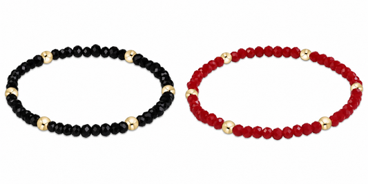 Two beaded enewton gameday flirty presence stretch bracelets on a white background: one made of faceted black beads with gold spacer beads, and the other made of faceted red beads with gold spacer beads.