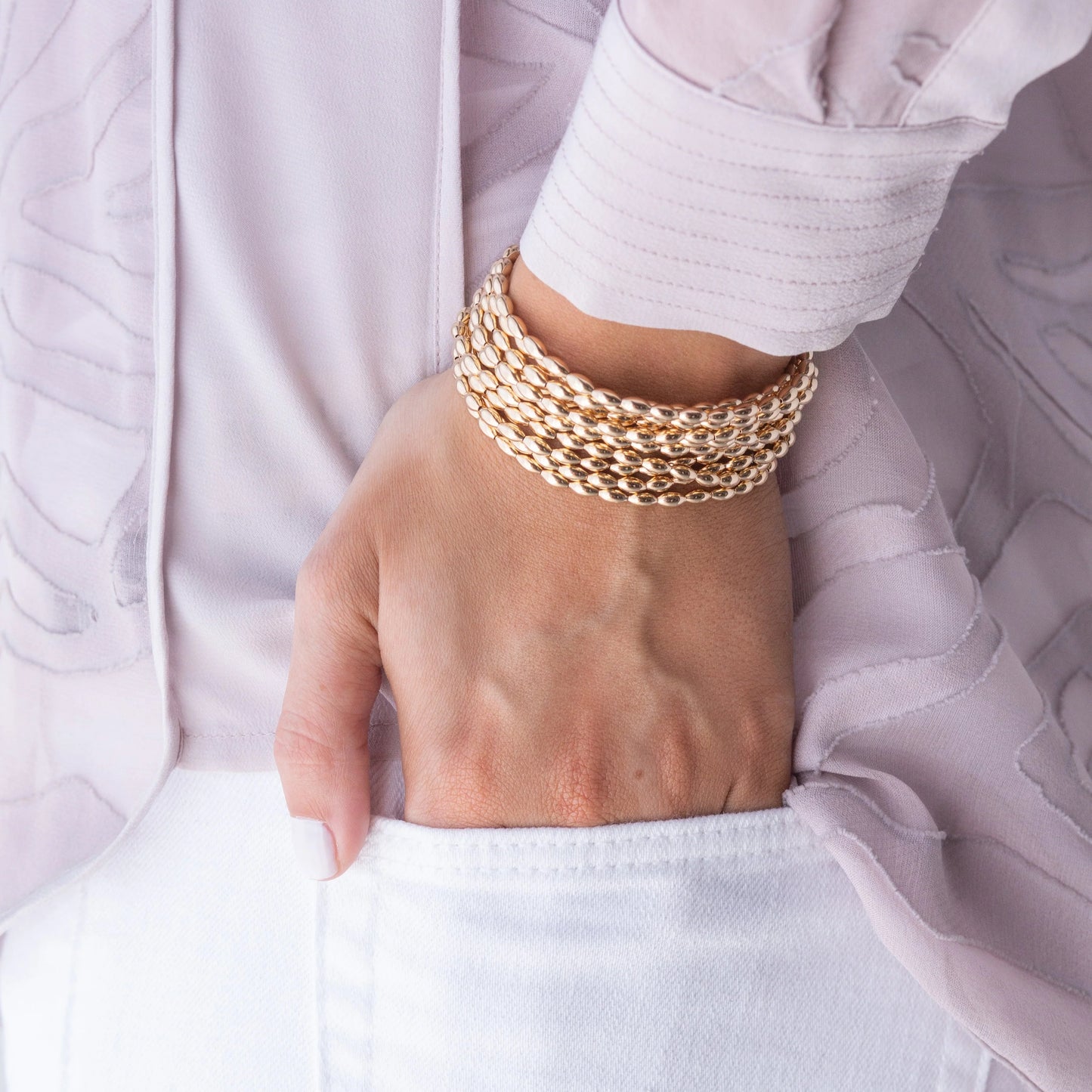 Model wearing several eNewton Harmony Small Gold Bead Bracelets 