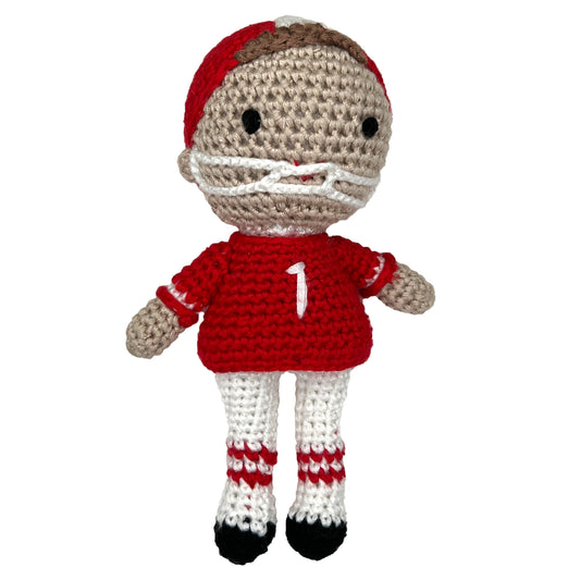 A crocheted football player rattle dressed in a red and white uniform with the number 1 on its shirt.