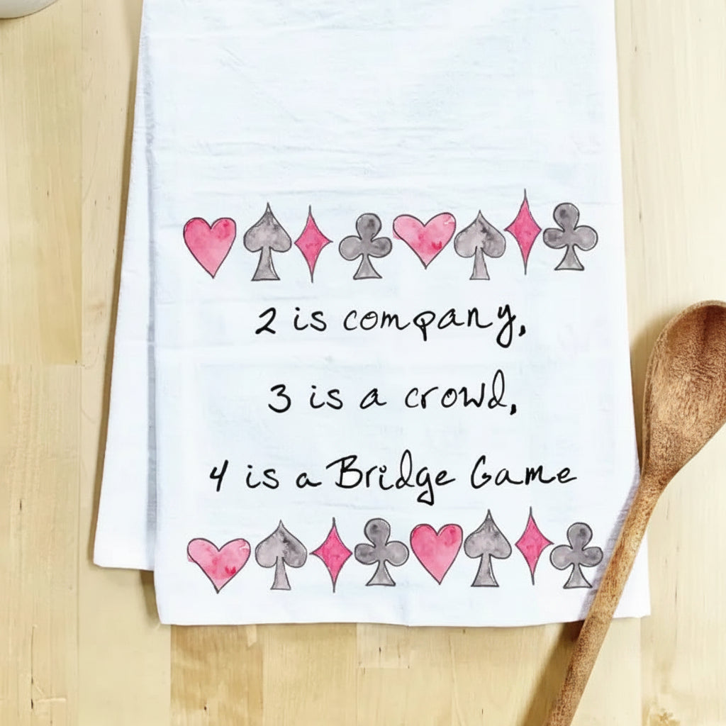 Tea towel with card suit symbols and text  about a bridge game on a wooden surface