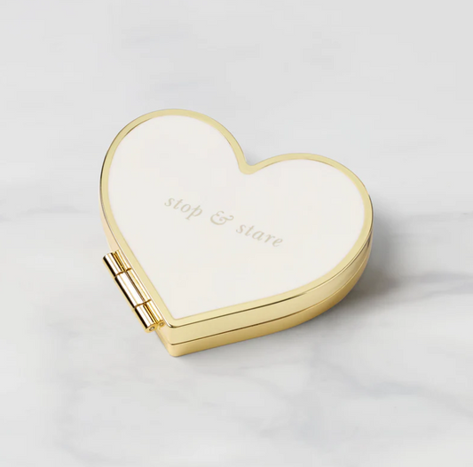 Heart-shaped cream compact mirror with gold frame and the words stop & stare