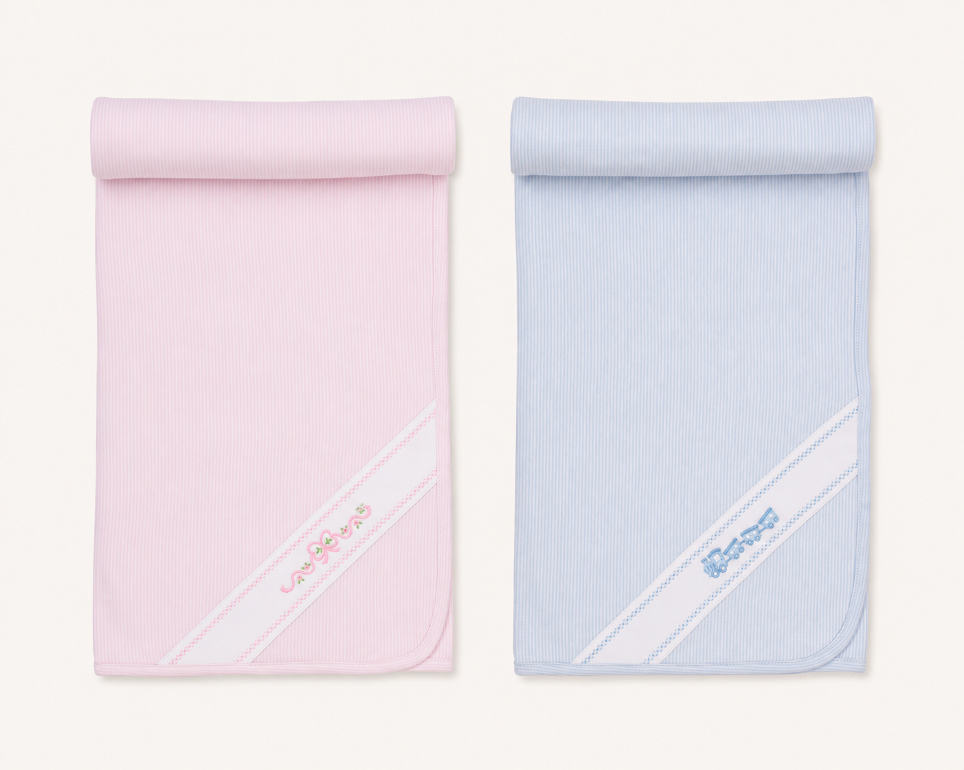 Two folded ribbed kissy kissy classic treasures baby blankets, one light pink and one light blue, each featuring a diagonal white stripe with embroidered lettering near the bottom corner, displayed side-by-side on a light cream background.