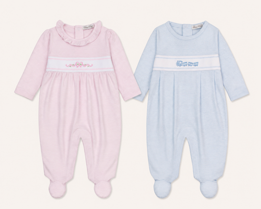 Two long-sleeve Kissy Kissy Classic treasures baby footed sleepers side by side on a light cream background. The left sleeper is light pink with a white smocked band featuring pink embroidered letters.