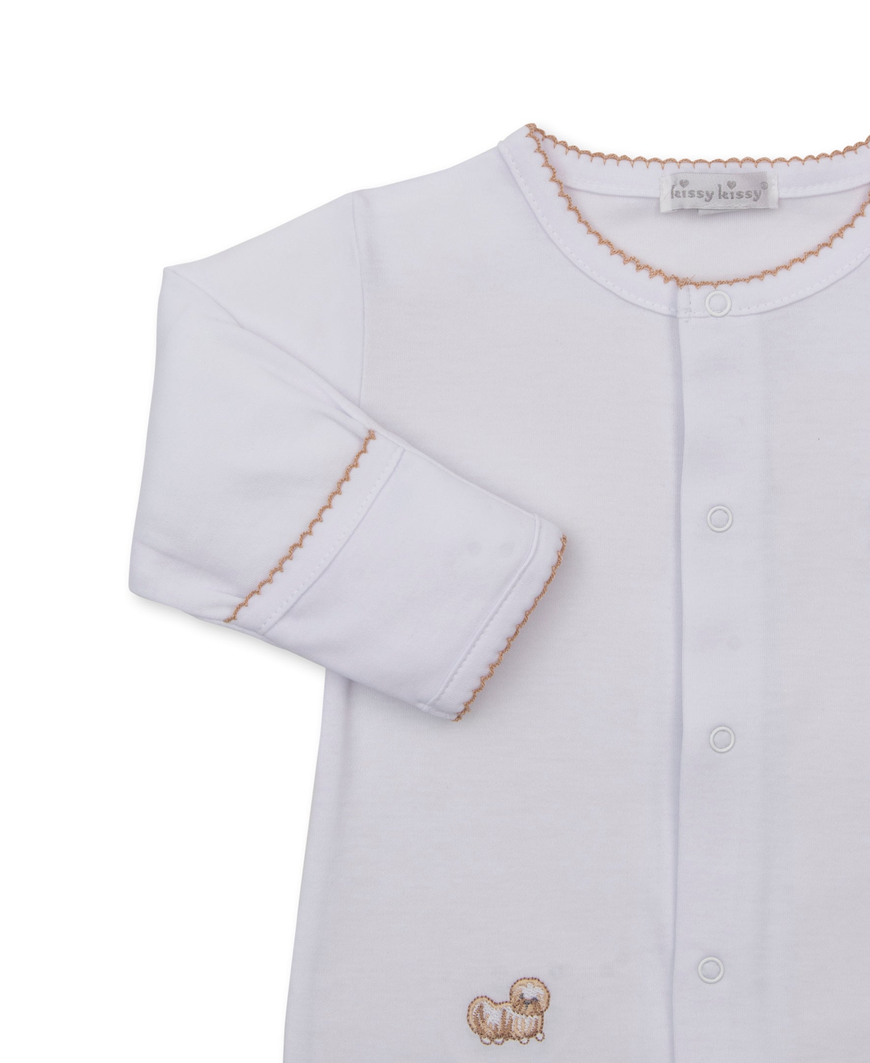A white long-sleeve baby footie with a button-front closure, scalloped beige trim around the collar and cuffs, and a small beige embroidered puppy motif near the lower front.