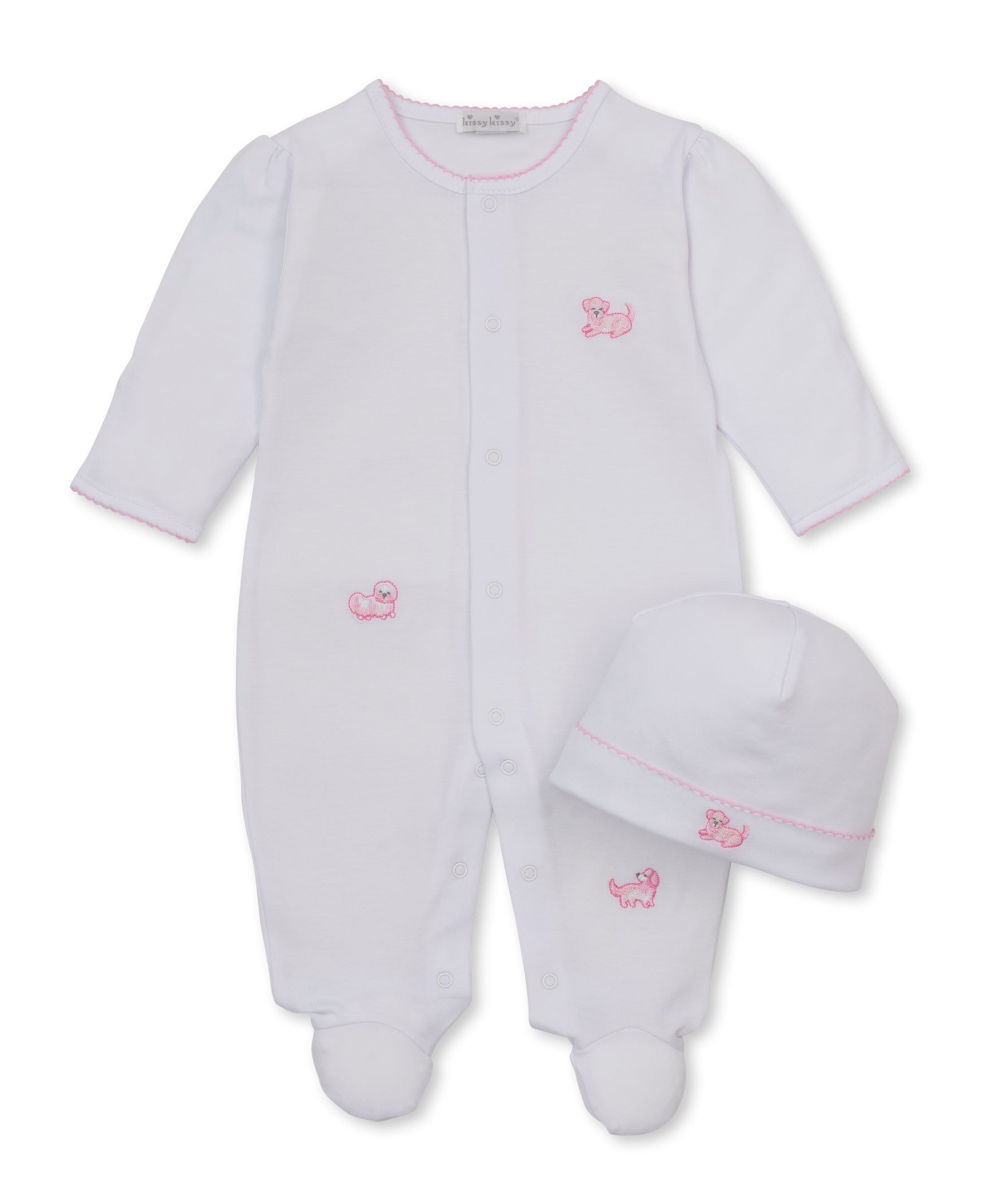 A white baby footed sleeper with long sleeves and a matching white beanie hat, both featuring small pink embroidered puppy motifs and pink trim, displayed on a clean white background.