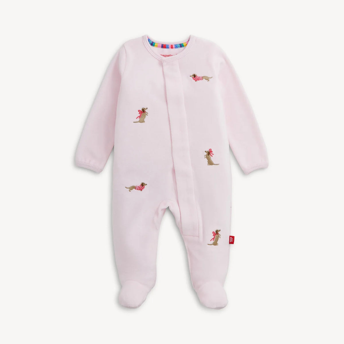 A light pink baby footed sleeper with long sleeves and an all-over print of small dachshund dogs wearing pink bows, shown against a plain off-white background.