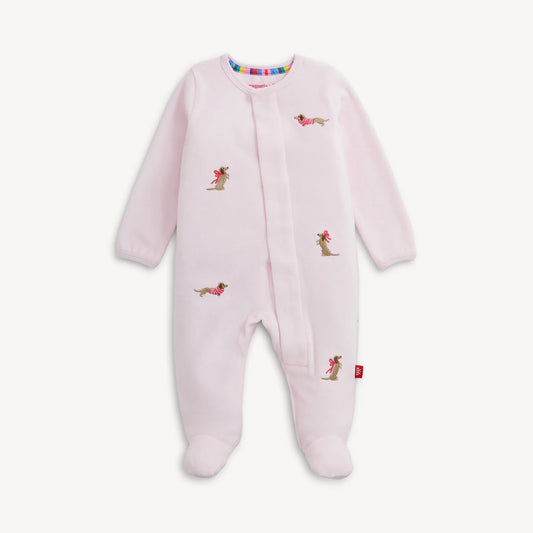 A light pink baby footed sleeper with long sleeves and an all-over print of small dachshund dogs wearing pink bows, shown against a plain off-white background.