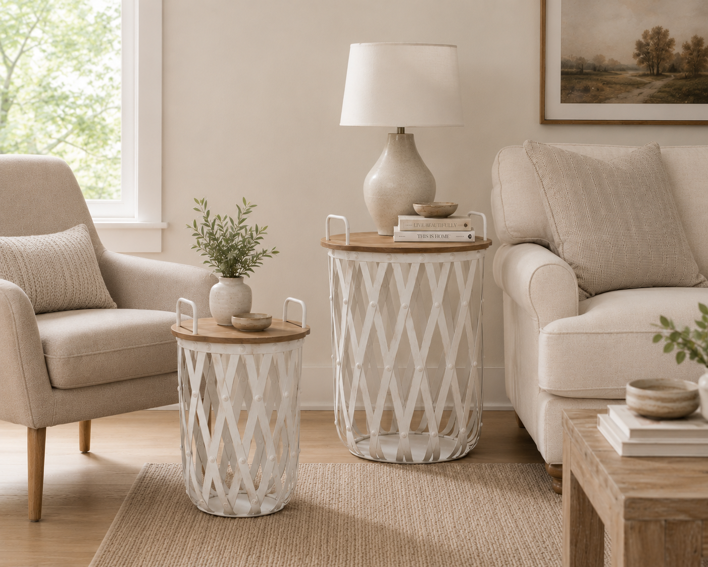 A styled living room scene showing two white lattice-patterned melrose side tables with light wood tops. One table holds a small vase with greenery and a bowl, while the larger table supports a cream ceramic lamp and books.