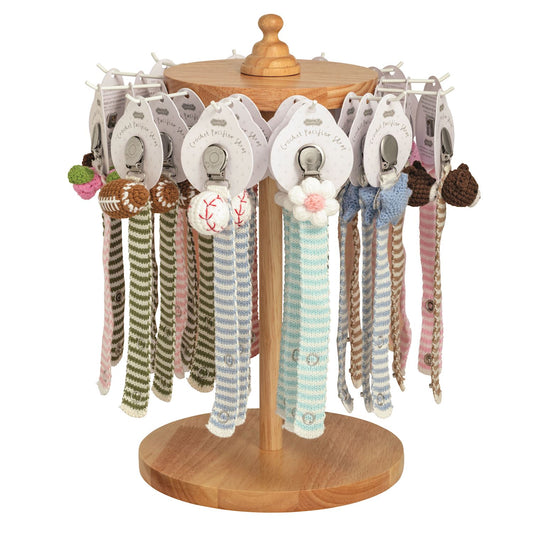 Wooden display stand with baby crochet pacifier straps by Mudpie pacifiers.
