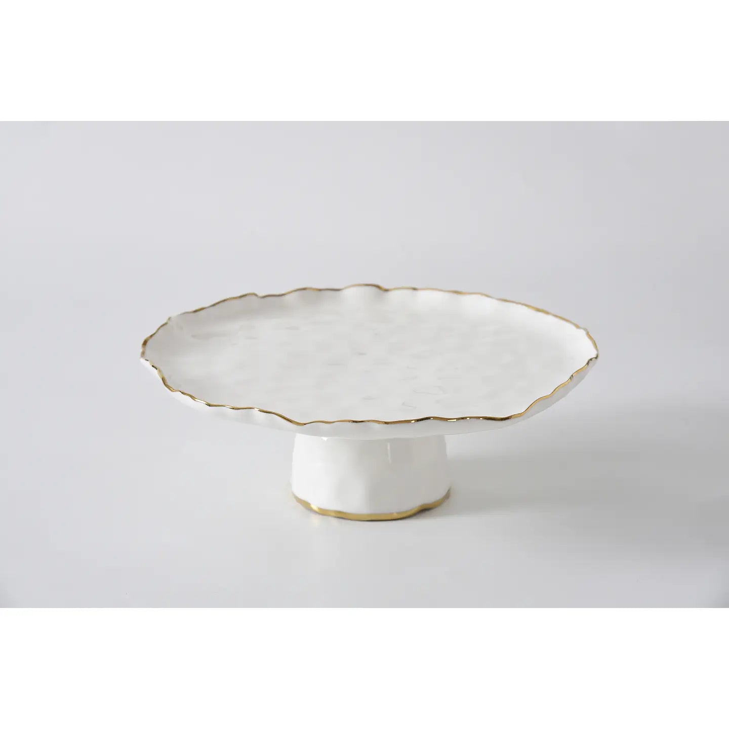 White ceramic cake stand with scalloped edge and gold trim