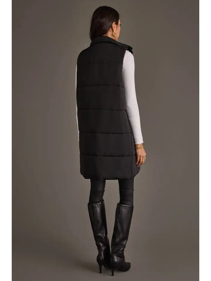 Person wearing a long black puffer vest by Panache on a gray background