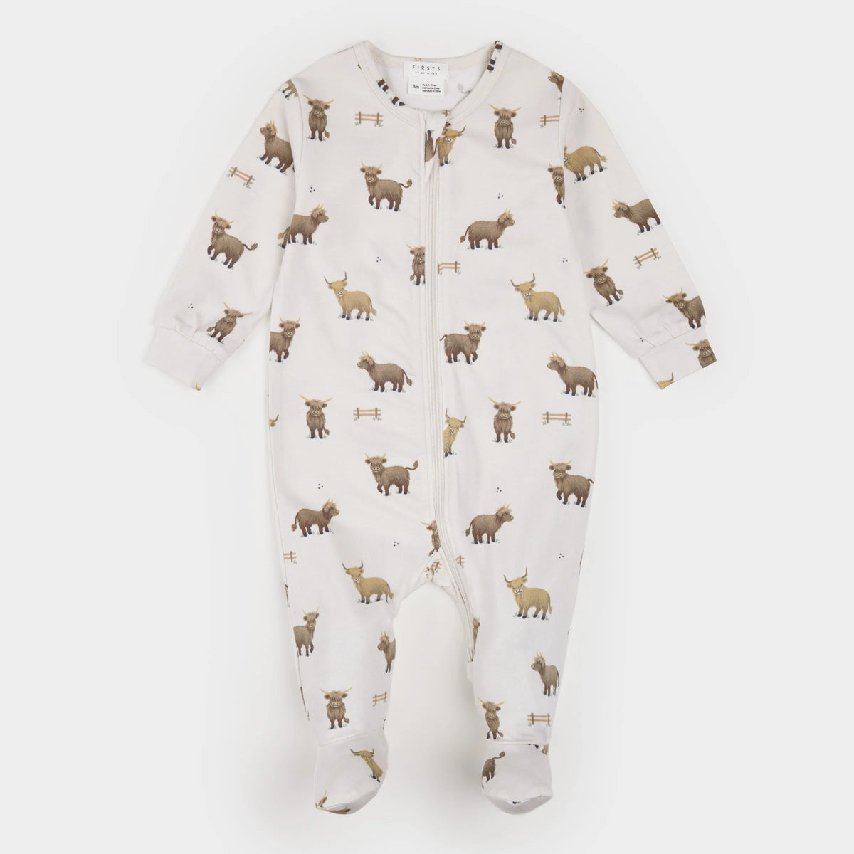 A baby footed sleeper in off-white with an all-over print of brown and tan highland cows and small fences, shown flat against a light gray background.