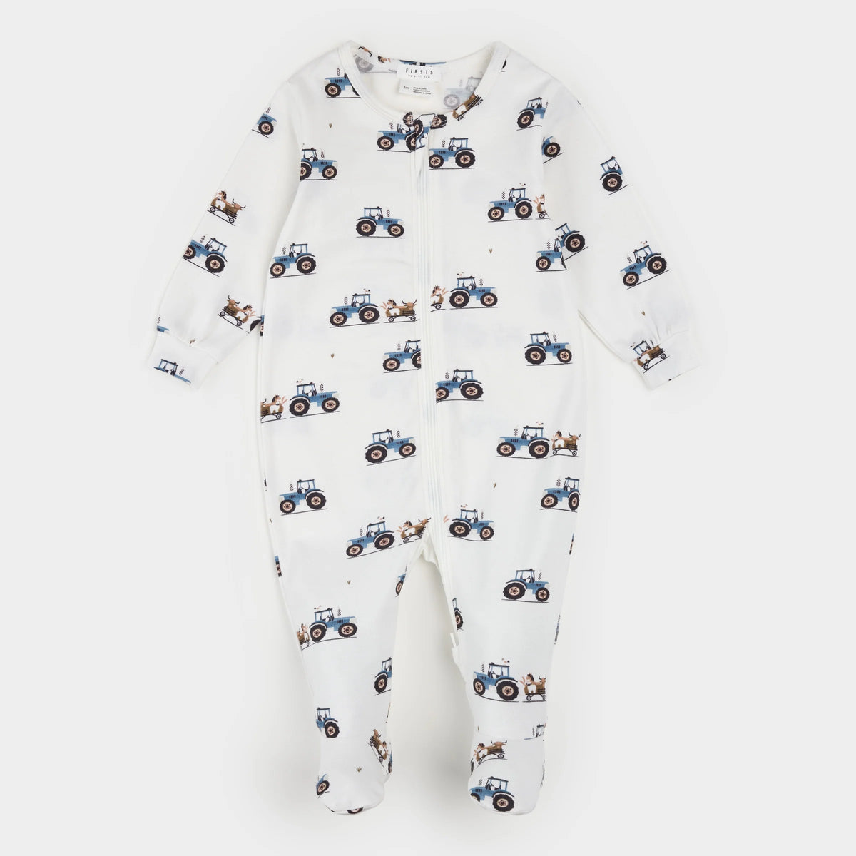 A baby footed one-piece sleeper in white, featuring an all-over print of blue tractors and small brown animals, displayed flat against a light gray background.